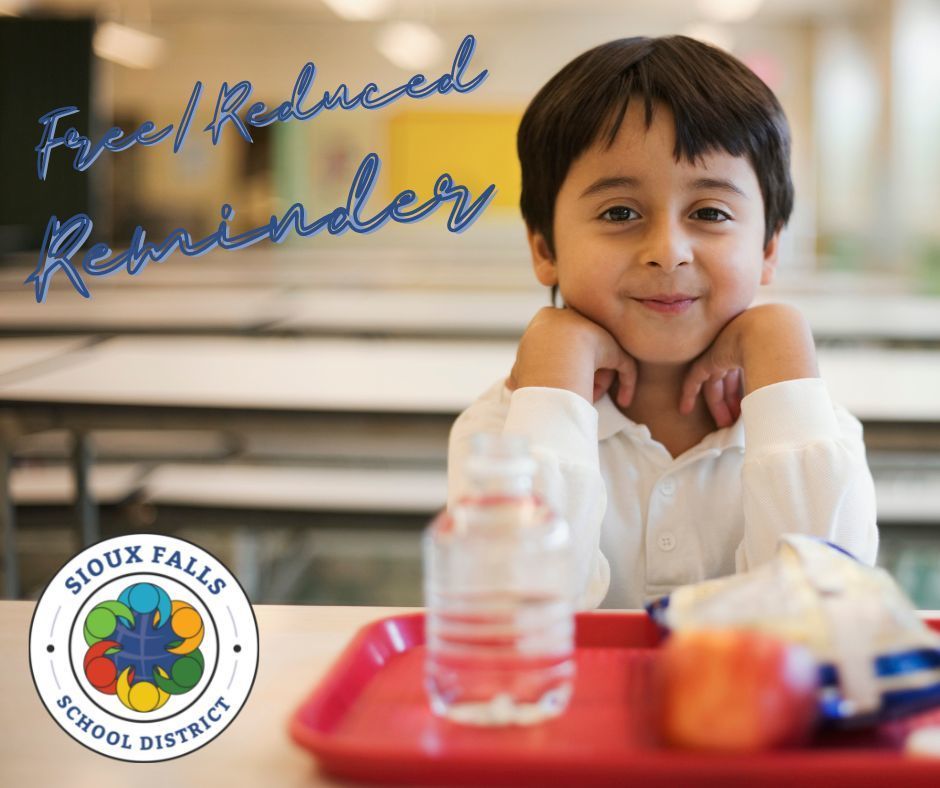 young kid sitting in front of a lunch tray smiling