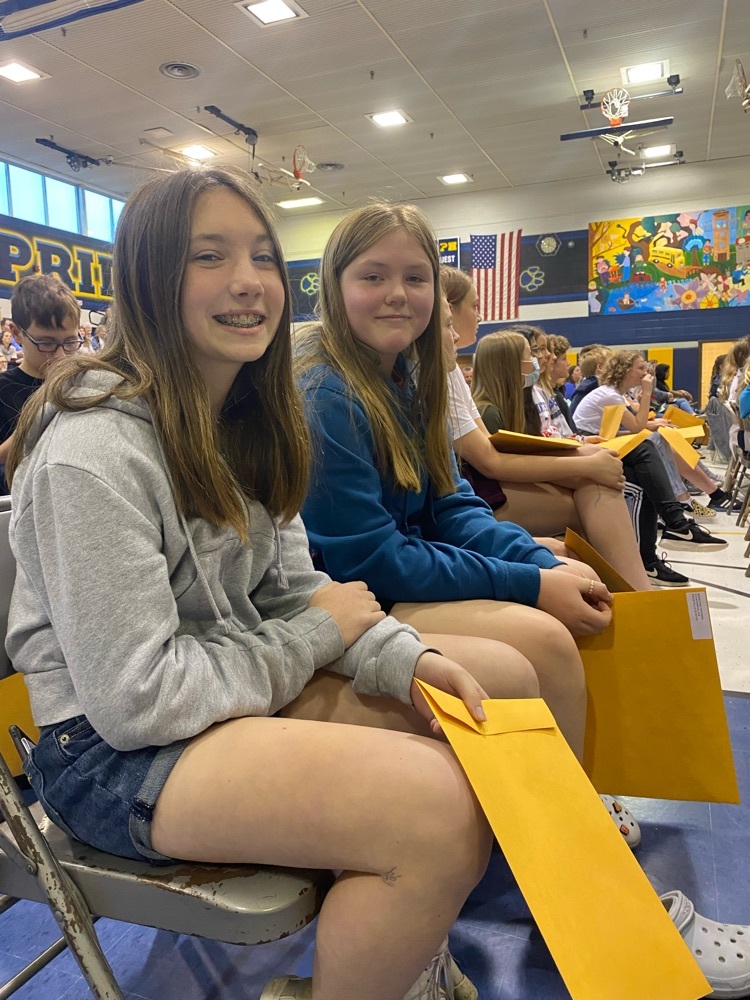 two students sitting in chairs with manila envelopes