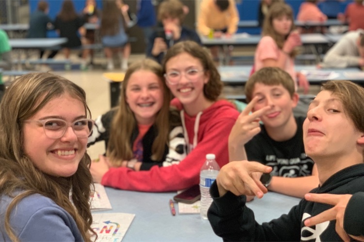 five students sitting at a table smiling